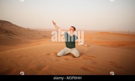 The guy throws sand over himself in the desert. The desert is next to Dubai. UAE. Stock Photo