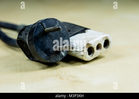 Electric cables, plugs and connectors on a wooden workshop table. Accessories and electrical components. Black background. Stock Photo
