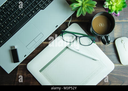 Top view of office stuff graphic design with pen mouse pad laptop wireless mouse and coffee cup on wooden table.Concept graphic design workplace Stock Photo