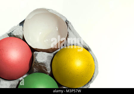 closeup shot with colorful cardboard container with chicken eggs, one is broken, four eggs painted in different colors. Easter concept Stock Photo