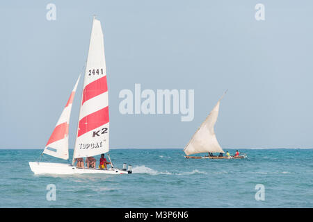 JAMBIANI, ZANZIBAR - DEC 22, 2017: Tourists on modern sport catamaran and fishermen on traditional wooden dhow boat in background sailing near Jambian Stock Photo