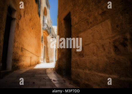 A typical narrow and historical road inlcuding cobblestone walls in Mdina, Malta. Stock Photo