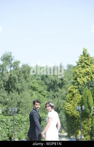 Beautiful dark haired Bride and Groom on a styled Wedding day- traditional white dress/black suit- Art Deco feel- bright sunny day Stock Photo