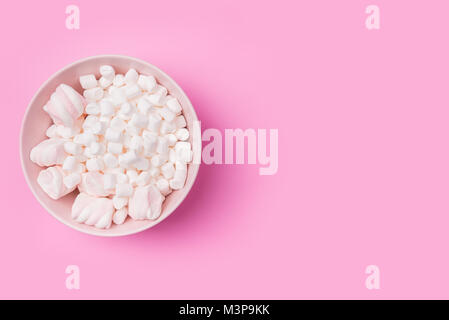 White Fluffy white marshmallows in bowl isolated on pink background. Top view image. Copyspace for your text. Stock Photo