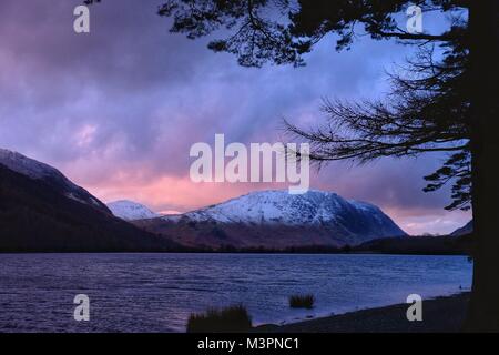 Buttermere, Cumbria, UK  12th  February. 2018.  After a cold day in the Lake District heavy sky’s and a setting sun combine to produce a stunning sunset on Buttermere. Credit: Tom Corban/Alamy Live News Stock Photo