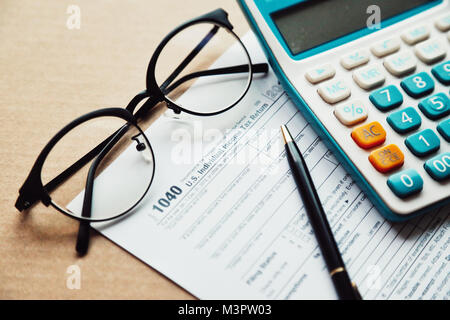 Close up income tax return planning ,1040 tax form, with calculator, pen and eye glasses place on the wooden table. Stock Photo