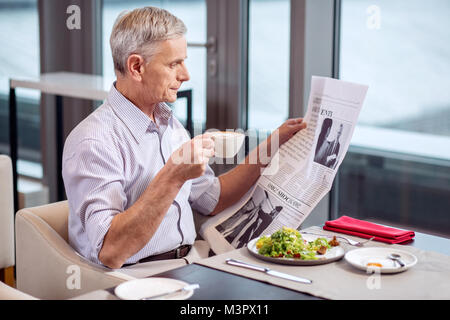 Concentrated mature man finishing breakfast Stock Photo