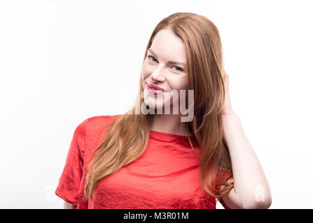 Charming ginger-haired woman posing with her hand in hair Stock Photo