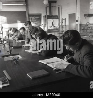 1950s, historical, young male science students sitting at a work bench in a laboratory at a technical college writing notes, England, UK. These colleges offered further education to those leaving secondary modren schools. Stock Photo