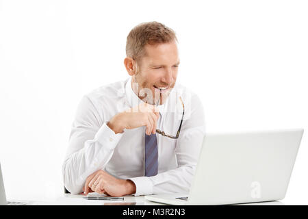 Middle aged financial agent seems deep in thought while sitting at desk and working on laptop. Businessman wearing shirt and tie. Isolated white backg Stock Photo