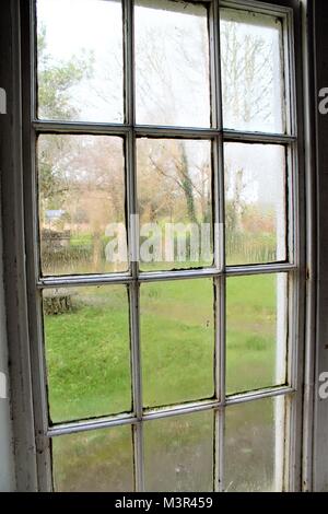Condensation on a church window looking out onto the cemetery. Stock Photo