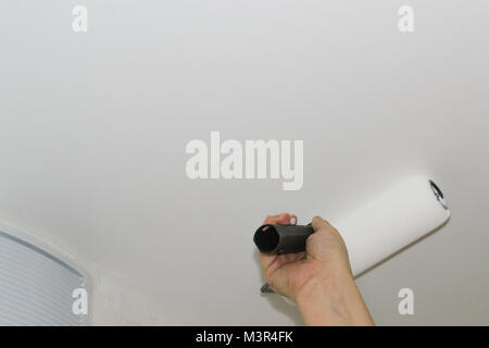 Paint the ceiling a woman's hand paints the ceiling Stock Photo