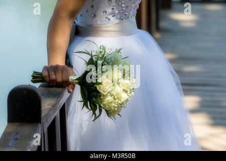 Close view of beautiful wedding bouquet with white roses in a hand of a bride (soft focus). Stock Photo