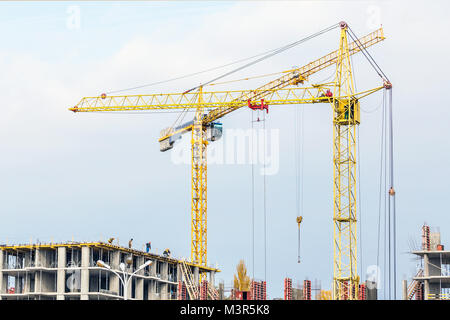Several cranes and buildings against blue sky. Construction site of hightower structure. Abstract construction background Stock Photo