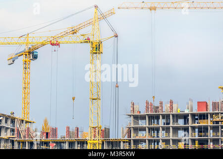 Several cranes and buildings against blue sky. Construction site of hightower structure. Abstract construction background Stock Photo