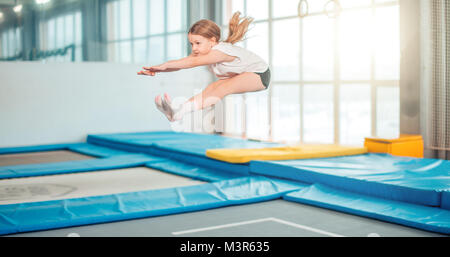 Girl jumping high in striped tights on trampoline. Stock Photo