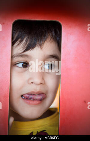 Brunette boy putting funny faces in an outdoor park Stock Photo