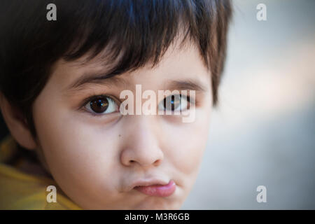 Brunette boy putting funny faces in an outdoor park Stock Photo