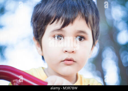 Brunette boy putting funny faces in an outdoor park Stock Photo