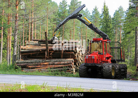 KOSKI TL, FINLAND - AUGUST 16, 2014: Sisu forestry forwarder stacking wood by road. Ca. 95% of Finnish production forests are certified under the Finn Stock Photo