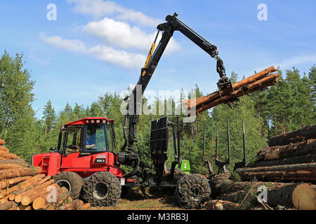 RAASEPORI, FINLAND - AUGUST 17, 2014: Unidentified machine operator stacking up wood with Komatsu 830.3 forwarder. Ca. 95% of Finnish production fores Stock Photo
