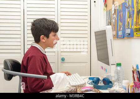 Schoolboy working on homework on computer at home,Surrey,Uk Stock Photo