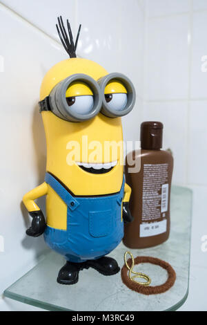 A  yellow and blue minion stands on a glass shelf in a bsthroom. Stock Photo