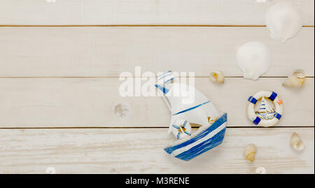 Table top view aerial image of accessories to travel beach on summer background concept.vintage sailboat with many shell on modern rustic white wooden
