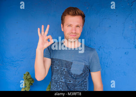 Satisfied caucasian young man showing okay sign Stock Photo