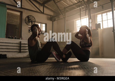 fitness couple doing sit ups together in health club. People doing abs workout in gym. Stock Photo