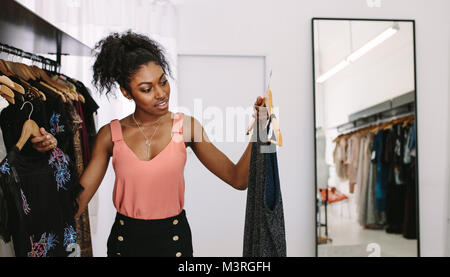 Female fashion designer looking at designer dresses in her fashion studio. Customer comparing dresses in a fashion boutique. Stock Photo