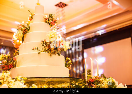 Candlestick and wedding cake on the glass table at the stage in wedding ceremony. Wedding Ceremony tools and decorations concept. Stock Photo