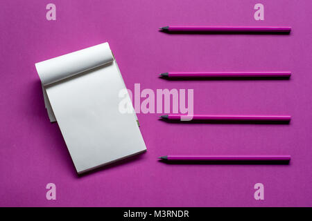 Top view notepad with pencils and copy space on pink paper background. Stock Photo