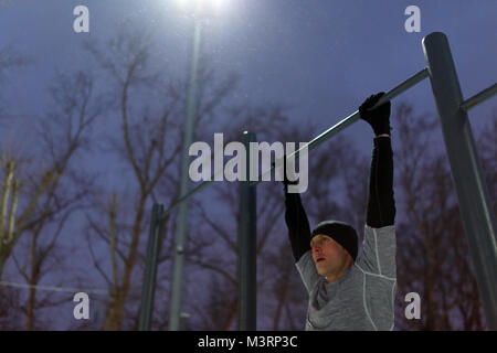 Image of athlete pulling up on bar in evening Stock Photo