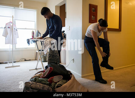 Airman 1st Class Ozzie Galvan (left) helps his wife, Airman 1st Class Alexandra Ayub, prepare for a four-day deployment by ironing and packing her clothes while she dresses at their home at Francis E. Warren Air Force Base, Wyoming. Ayub, a missile chef, regularly deploys to provide meals to the Airmen stationed at missile alert facilities that are many miles away from her home base. (U.S. Air Force photo/Staff Sgt. Andrew Lee) 160516-F-NL936-025 by AirmanMagazine Stock Photo