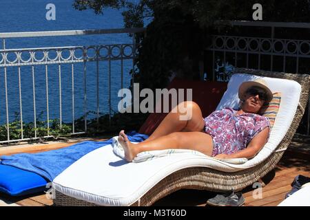 28TH JULY 2017, SOVALYE ISLAND,TURKEY:An english lady relaxing on a sunbed next to an infinity pool while on vacation on sovalye island, turkey Stock Photo