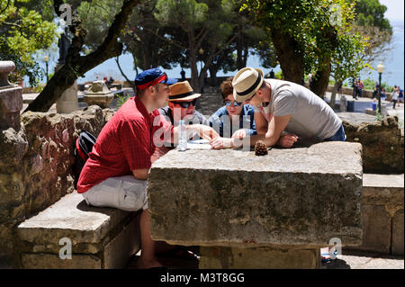 A group of friends examining closely at a Guide Map in the ground of Lisbon Castle, Portugal Stock Photo