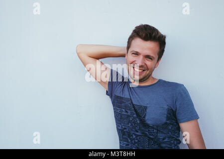 Caucasian man in blue shirt standing near wall and smile a little. Stock Photo