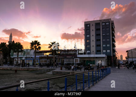 Larnaca, CYPRUS - January 2 2018: People by the waterfront in the city center of Larnaca in sunset light. View towards Saint Lazarus Church. LARNACA,  Stock Photo