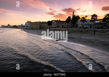 Larnaca, CYPRUS - January 2 2018: People by the waterfront in the city center of Larnaca in sunset light. View towards Larnaca castle and Kebir-Buyuk  Stock Photo