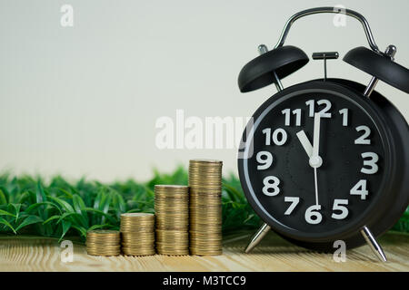 Steps of coins stack with vintage alarm clock on wooden working table with copy space for text, financial and business planning concept idea. Stock Photo