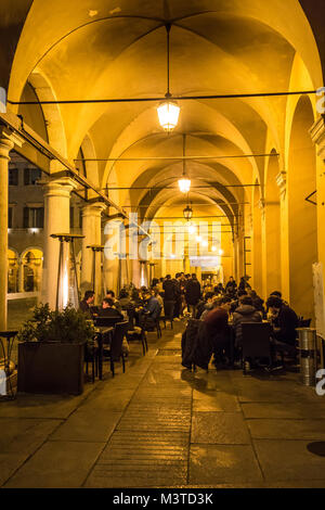 Cafes line a portico facing Piazza Grande at night in Modena Italy Stock Photo