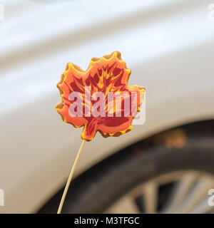 Delicious handmade cookie in the form of a maple leaf on the background of a car Stock Photo