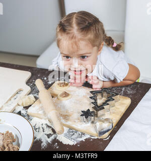 Little girl with her dirty nose helps her mother make dumplings Stock Photo