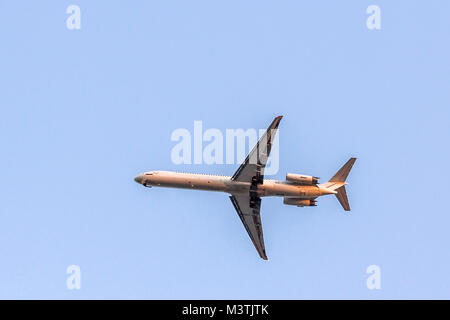 Flying commercial two engine airplane against clear blue sky. Passenger modern aircraft isolated on blue background. Stock Photo