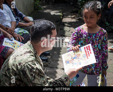 Cuscatlan, El Salvador (Sep. 2, 2016) - Lt. Alister Bryson, an entomologist assigned to Naval Environmental Preventive Medicine Unit 2, left, gives a child a coloring book at a temporary care site in Cuscatlan, El Salvador during Southern Partnership Station 2016 (SPS 16). SPS 16 is an annual series of U.S. Navy deployments focused on subject matter expert exchanges with partner nation militaries and security forces in Central and South America and the Caribbean. U.S. military teams work with partner nation forces during naval-focused training exercises, military-to-military engagements and co Stock Photo