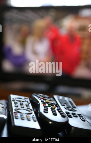 A range of remote controls for television, satellite, DVD and sound system, on the arm of a chair, in Peterborough, Cambridgeshire, on February 12, 20 Stock Photo