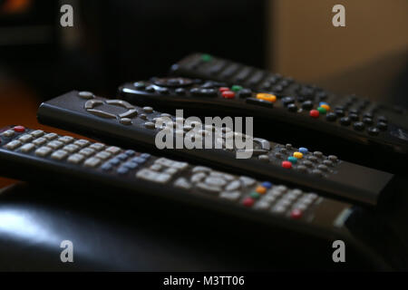 A range of remote controls for television, satellite, DVD and sound system, on the arm of a chair, in Peterborough, Cambridgeshire, on February 12, 20 Stock Photo