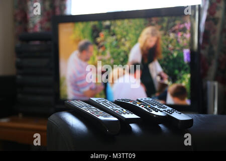 A range of remote controls for television, satellite, DVD and sound system, on the arm of a chair, in Peterborough, Cambridgeshire, on February 12, 20 Stock Photo