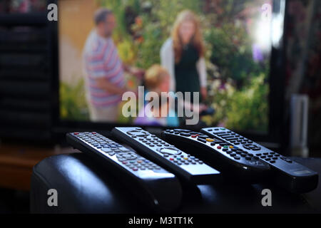 A range of remote controls for television, satellite, DVD and sound system, on the arm of a chair, in Peterborough, Cambridgeshire, on February 12, 20 Stock Photo